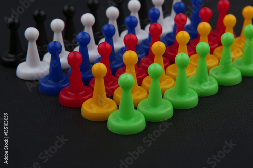 Colorful play figures. Board game pieces on black background.