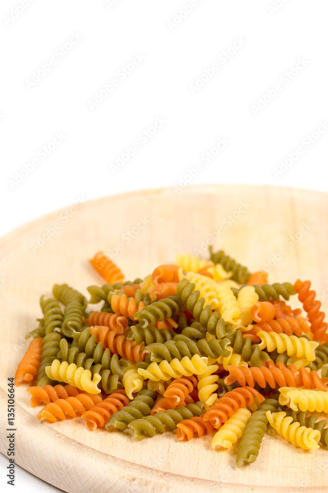 Raw colored macaroni on the wooden board with copy space Raw colored macaroni on the wooden board with copy space