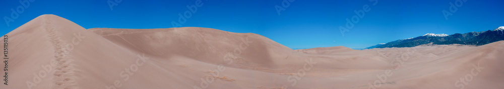 A panoramic photo of the sand dunes and mountains at Great Sand Dunes National Park in Colorado.