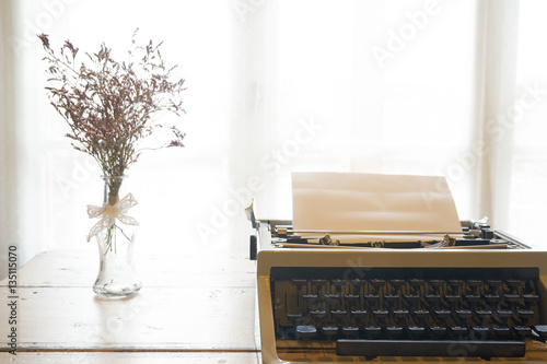 Vintage typewriter and dry flowers front a window 