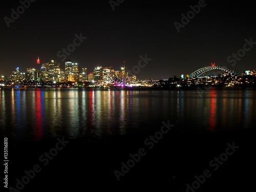 The lights of Sydney reflect in the harbor at night. © Nikki