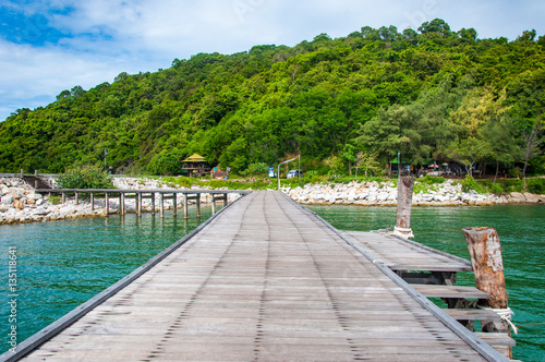 Beautiful Wooden Jetty with Dramatic Sky and Green Island Backg