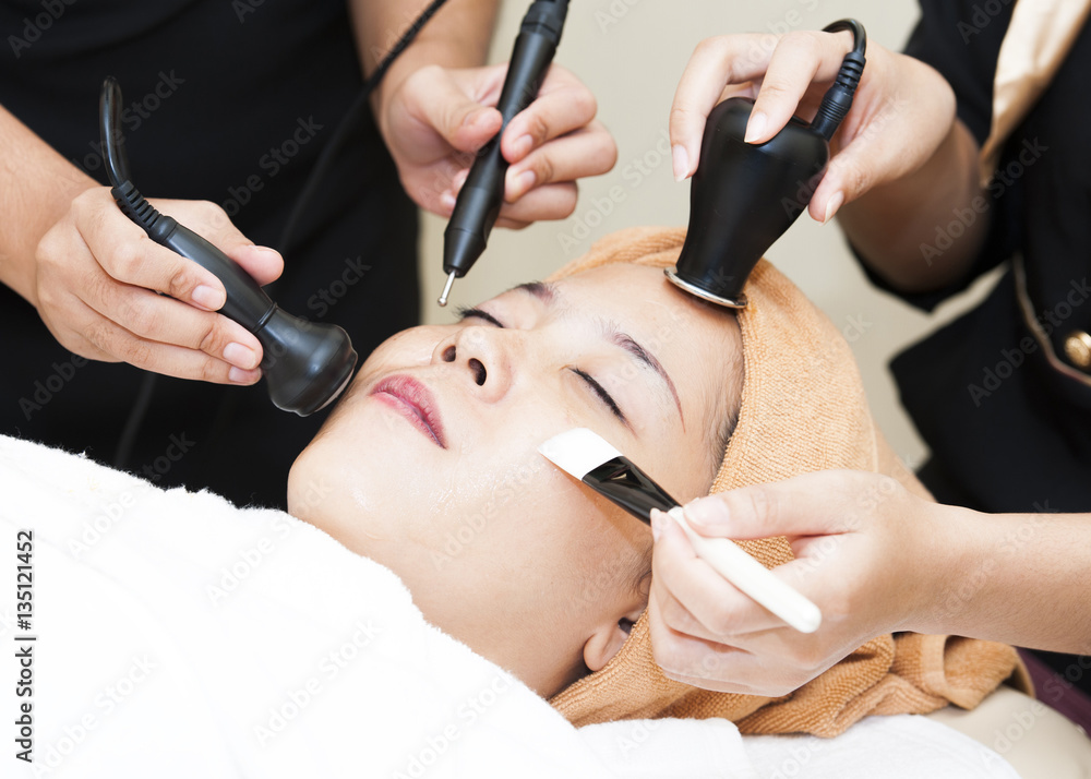 Beautiful young woman receiving facial mask of cucumber. Beautiful young woman receiving facial mask of cucumber.