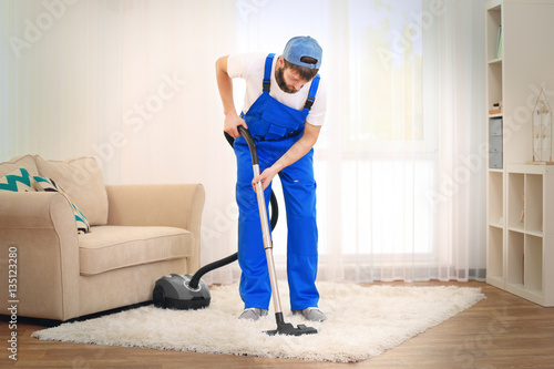 Young man hoovering carpet ...