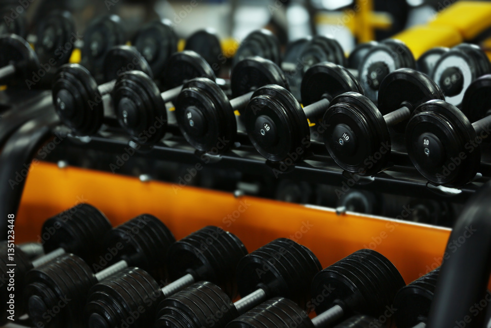 Rack with different dumbbells in gym, close up