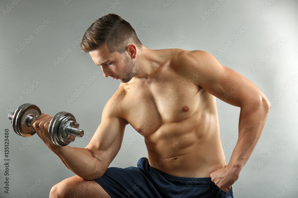 Sporty man doing exercises with dumbbell on light background Sporty man doing exercises with dumbbell on light background