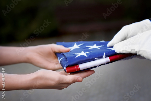 Hands holding folded American flag on blurred background photo