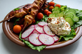 Chicken kebab with vegetables on a clay plate