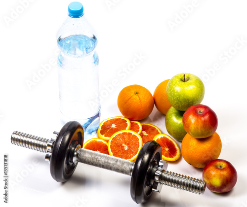 Concept of healthy active lifestyle. Heap of green and red apples and red oranges. Bottle of pure water. Fitness dumbbell in foreground. Sliced red orange. Healthy diet nutrition.