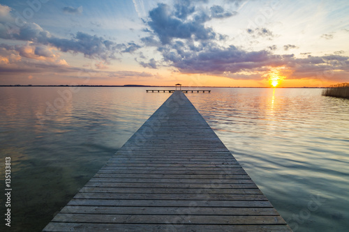 Fototapeta Naklejka Na Ścianę i Meble -  wooden pier overlooking the lake, the beautiful evening sky, colored by the setting sun
