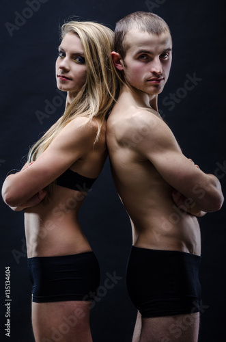 Sports man and woman in the dark. Beautiful muscular figure.