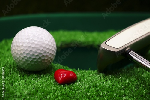 golf ball and heart are next to the hole 