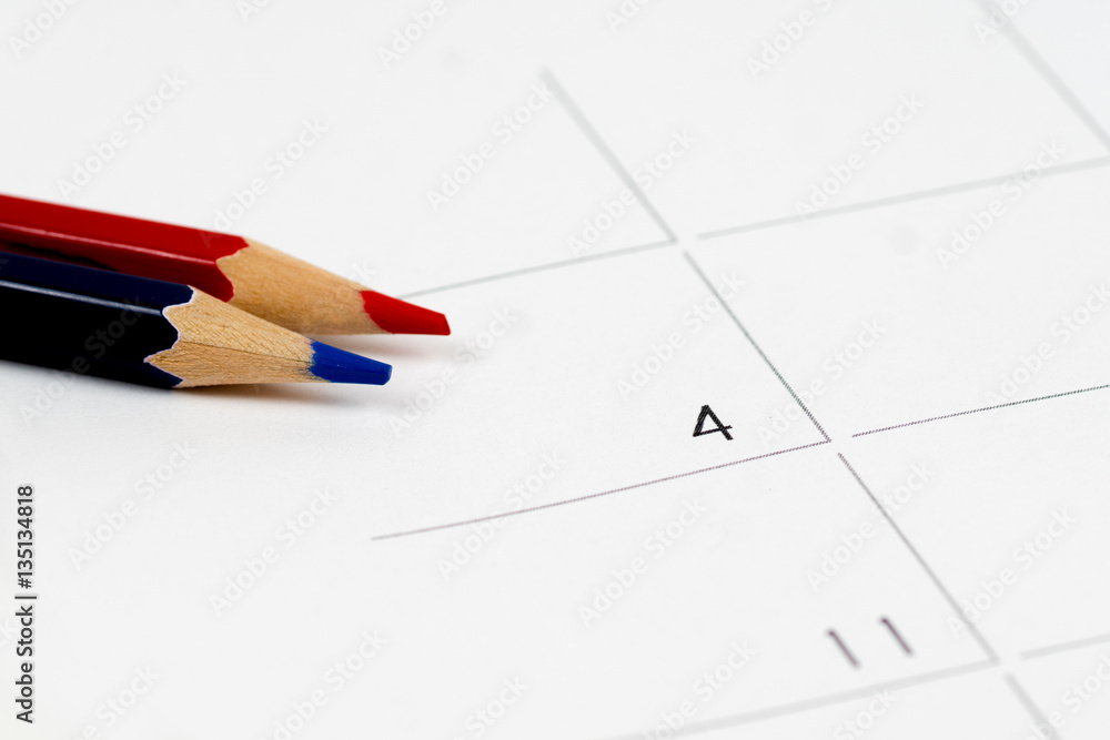 red and blue pencils on empty calendar grid red and blue pencils on empty calendar grid