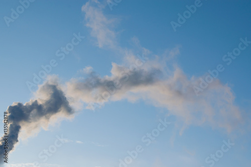 Black smoke from chimney on blue sky background