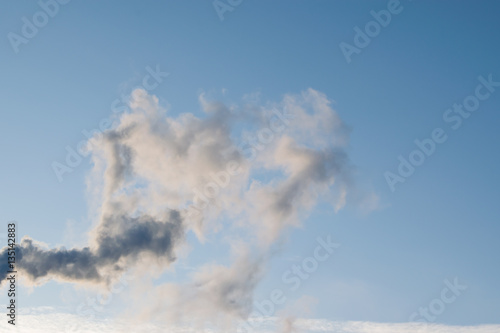 Black smoke from chimney on blue sky background