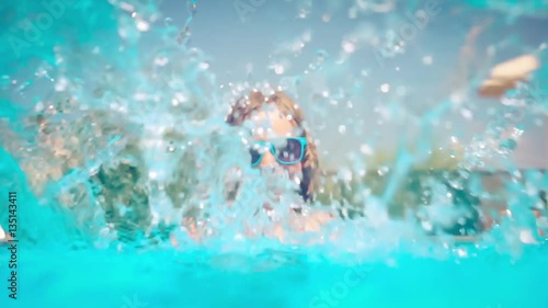 Happy child playing in swimming pool. Girl having fun outdoors. Summer vacation and holiday concept. Slow motion