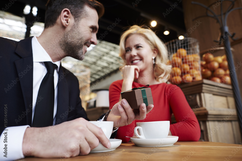 Handsome man giving woman gift over coffee meeting