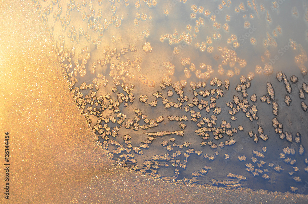 Winter background. Frosty pattern on window glass closeup in the sunlight.