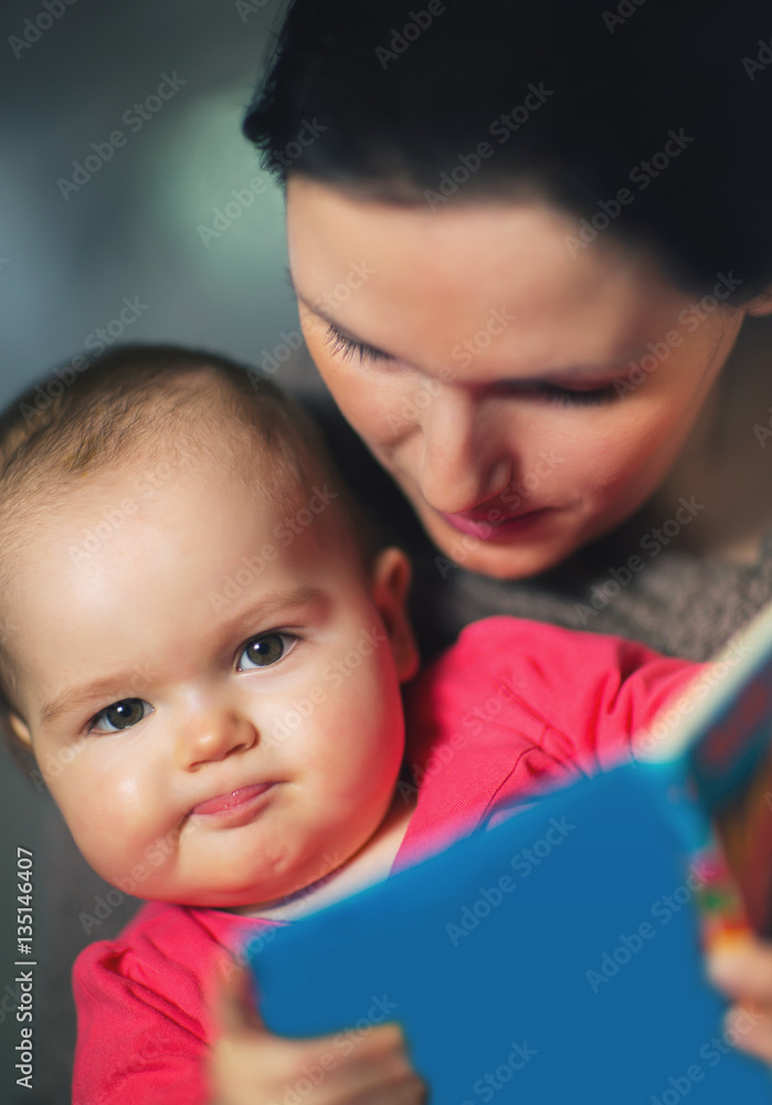 Charming mother showing images in a book to her cute little baby Charming mother showing images in a book to her cute little baby