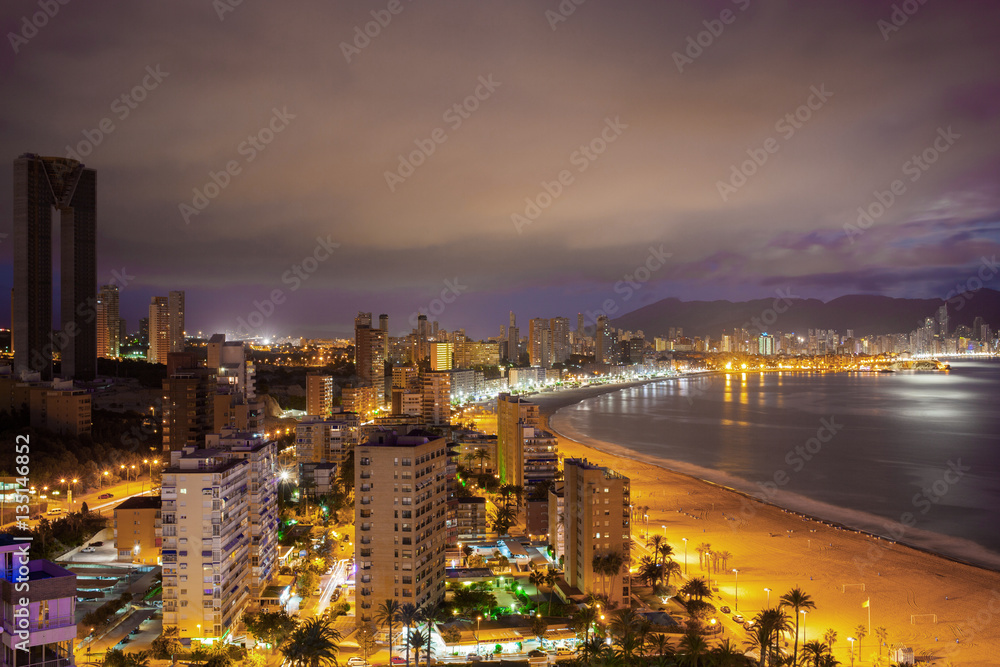 Panorama of the coastal city at sunset with lights reflected in sea