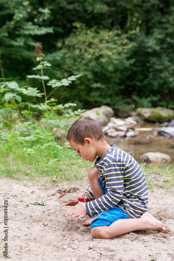 Child playing with sand by a river Child playing with sand by a river