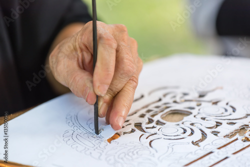 soft focus on old lady's hand making perforated ancient thai paper pattern