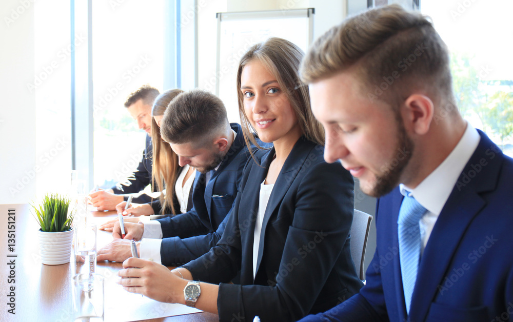 Smiling businesswoman looking at camera at seminar with her colleagues near by