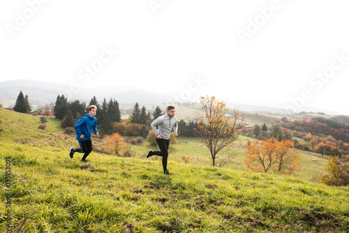 Two young hipster athletes running in sunny autumn nature