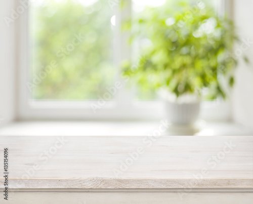 Light wooden table on defocuced spring window background