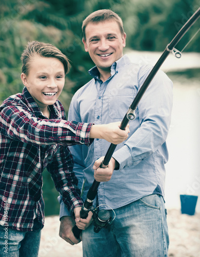 Boy with father fishing together on freshwater lake