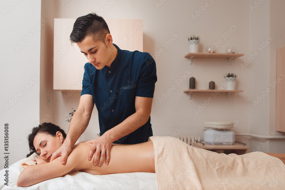 Fotka „Chiropractor diagnosing woman at office free space. Young male masseur making treatment massage for nude brunette with pain in back. Health, beauty, body care concept“ ze služby Stock | Adobe Stock