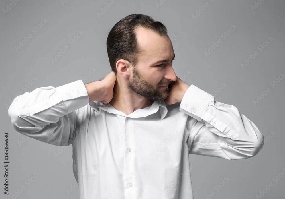 Handsome man suffering from neck pain on color background Handsome man suffering from neck pain on color background