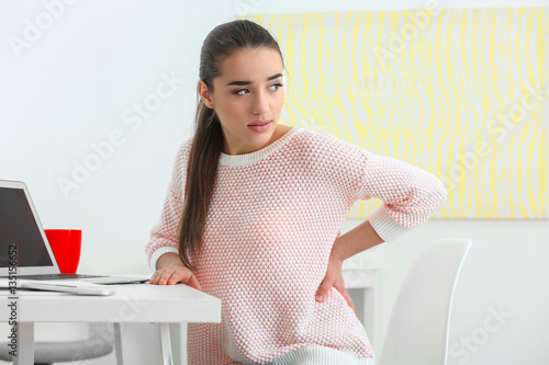 Canvas Print Beautiful young woman suffering from backache in office