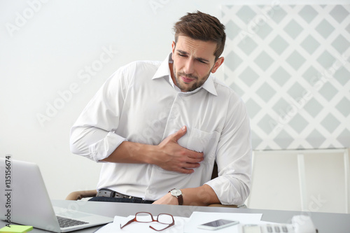 Obraz na plátně Handsome young man suffering from heartache in office