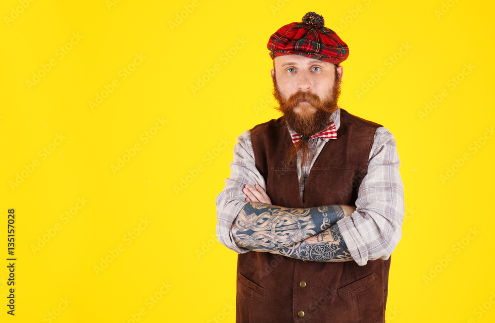 Young bearded man in plaid cap on yellow background Young bearded man in plaid cap on yellow background