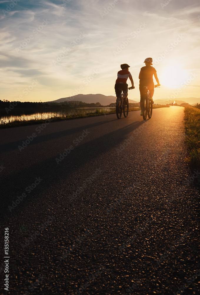 Obraz premium Two cyclists are on sunset road