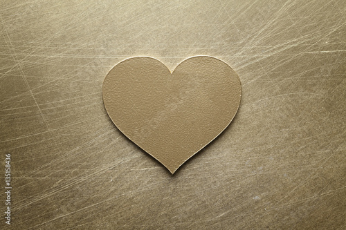 Golden metal heart on scratched surface