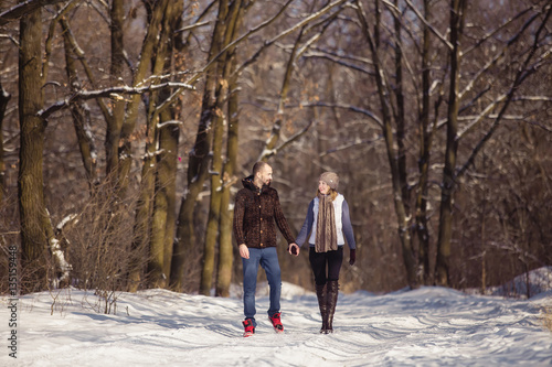 A young woman and a man walking in the winter park on a sunny day