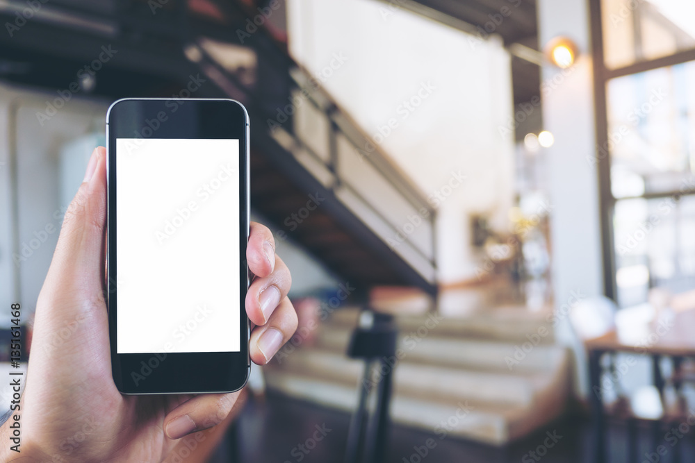 Mockup image of hand holding black mobile phone with blank white screen in cafe Mockup image of hand holding black mobile phone with blank white screen in cafe