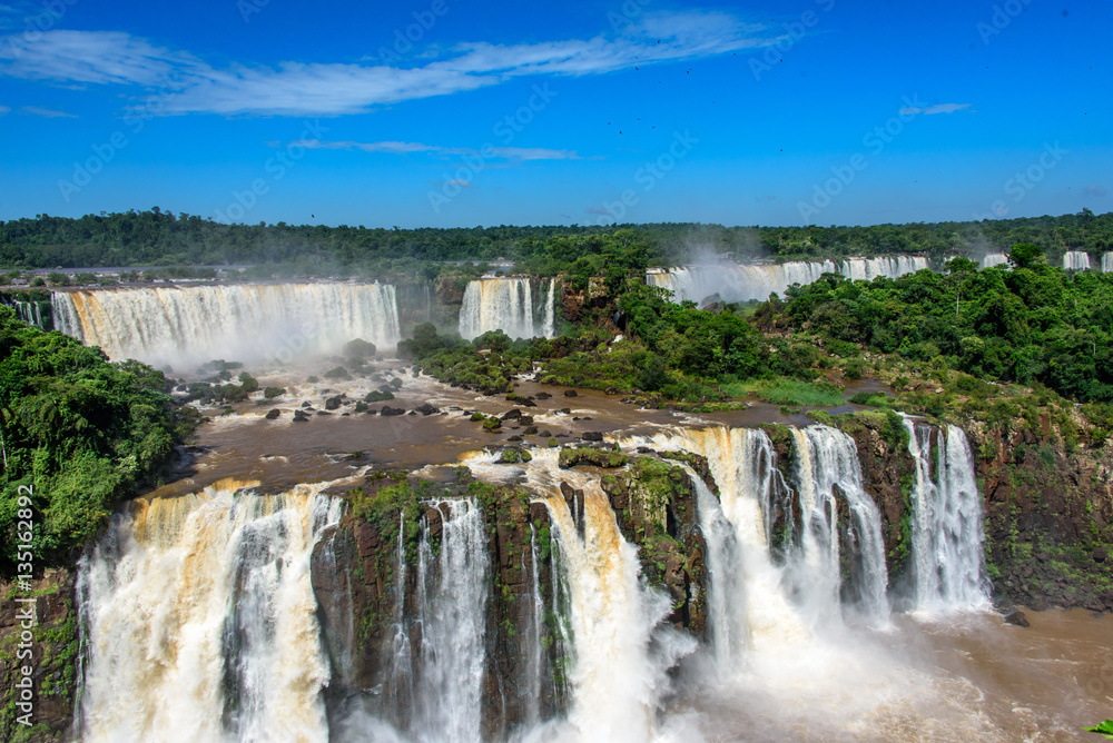 Aerial view of waterfalls cascade of Iguazu Falls with extensive tropical forest and powerful flows of water in Iguacu National Park, UNESCO World Heritage Site, Foz de Iguacu, Parana State, Brazil