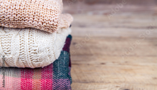stack of clothes from knitted knitwear on a wooden background