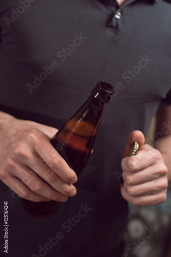 Closeup of male hands opening beer bottle