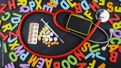 Stethoscope with medicine and syringe on blackboard