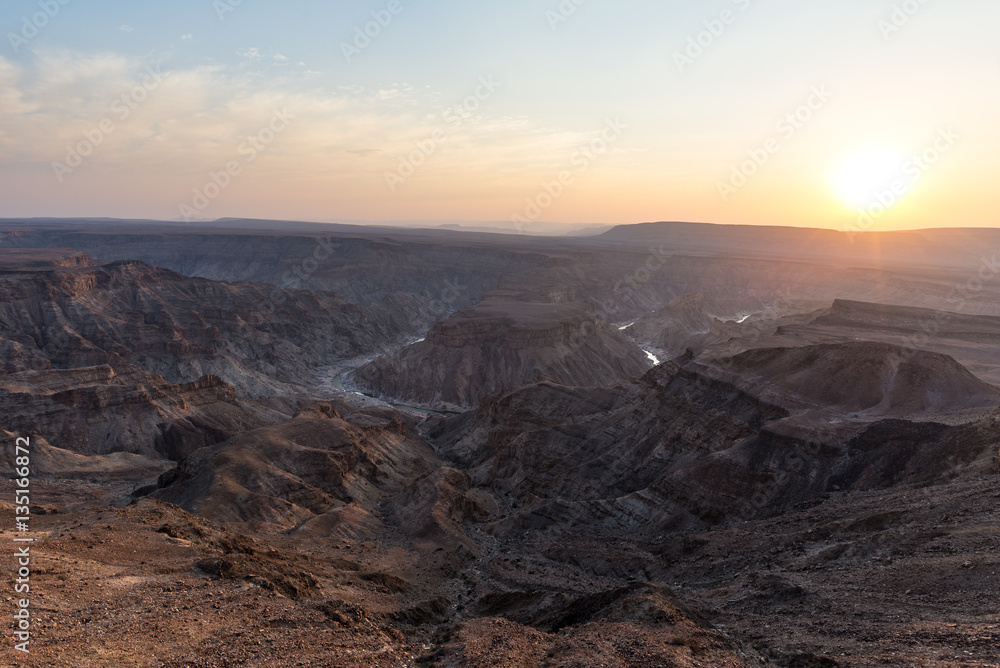 Fish River Canyon, scenic travel destination in Southern Namibia. Last sunlight on the mountain ridges. Wide angle view from above.