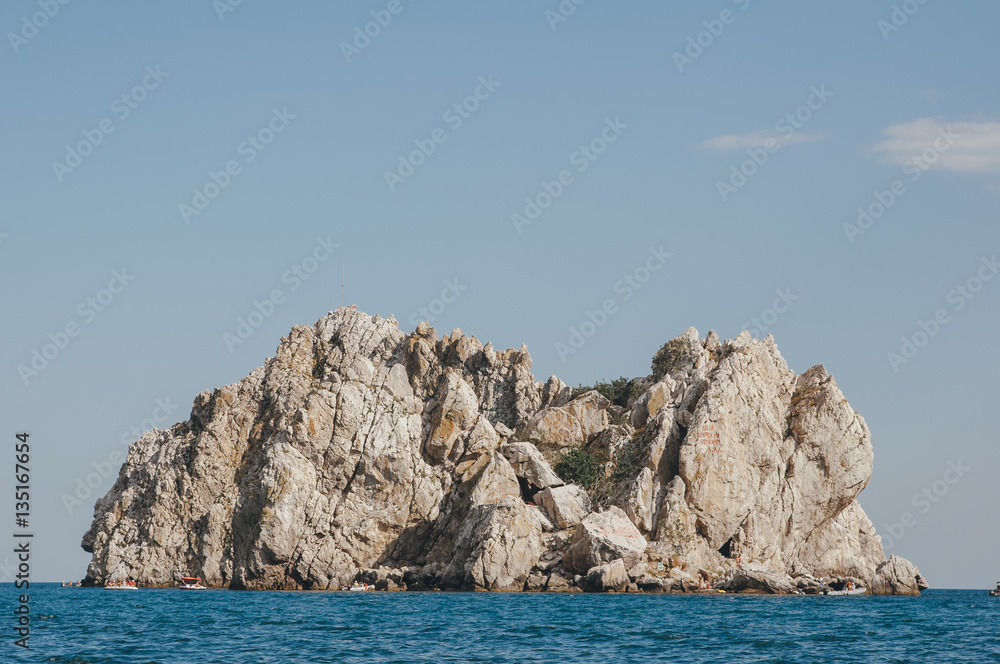 Rock on a background of blue sea. Beautiful seascape