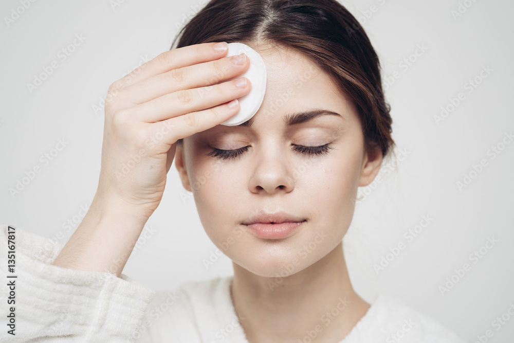 Fototapeta premium woman wipes her forehead with a cotton disc, closed eyes