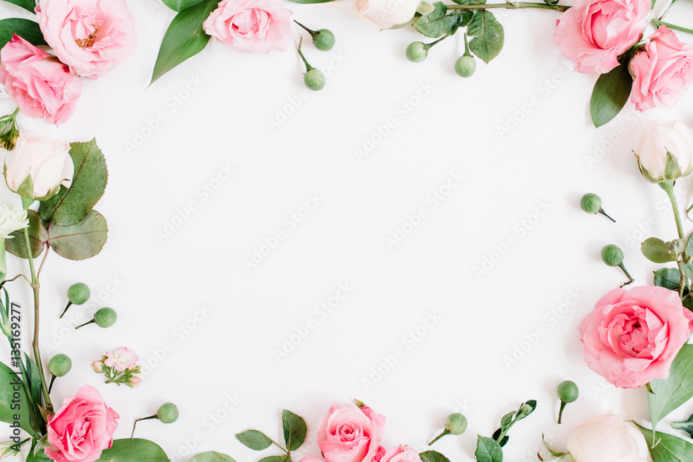 Round frame made of pink and beige roses, green leaves, branches on white background. Flat lay, top view. Valentine's background