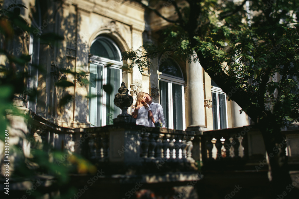 Look from afar at beautiful couple standing in the rays of light on the balcony
