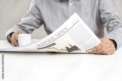 Man reading newspaper on table photo