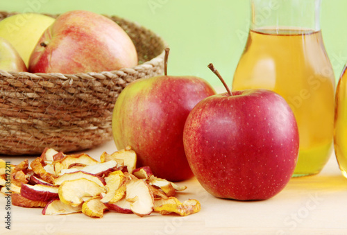 Fresh apples, dried apples and apple juice on wooden background.